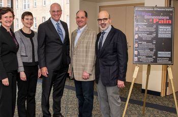 Five Neuroscience symposium speakers standing together next to a posterboard